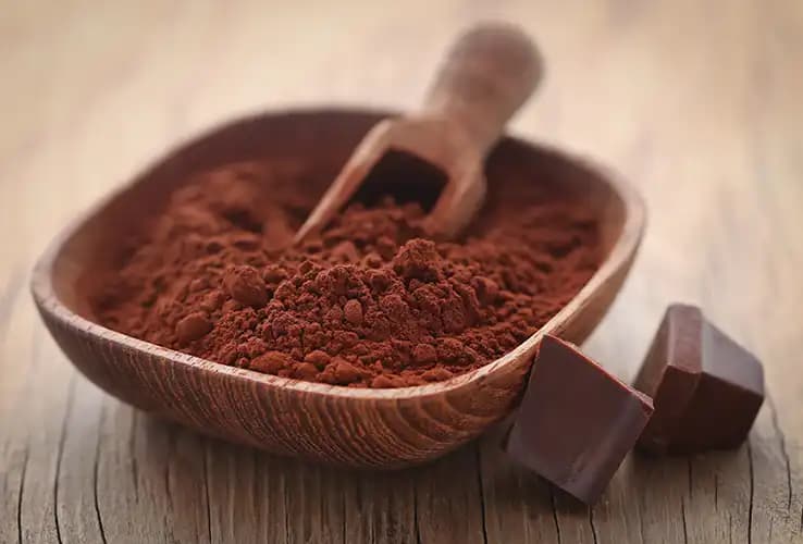 Cocoa powder in a wooden bowl with dark chocolate